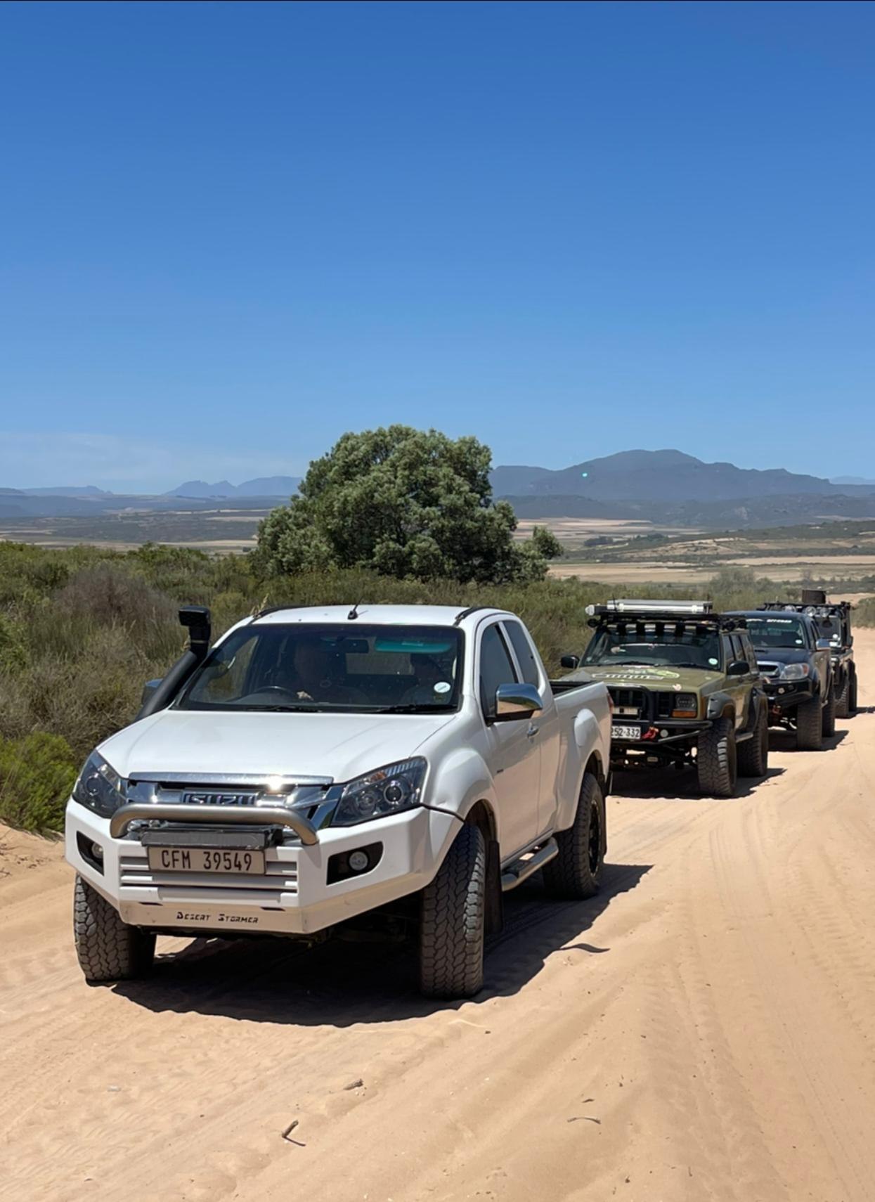 Convoy of 4x4 vehicles on a sandy mountain road