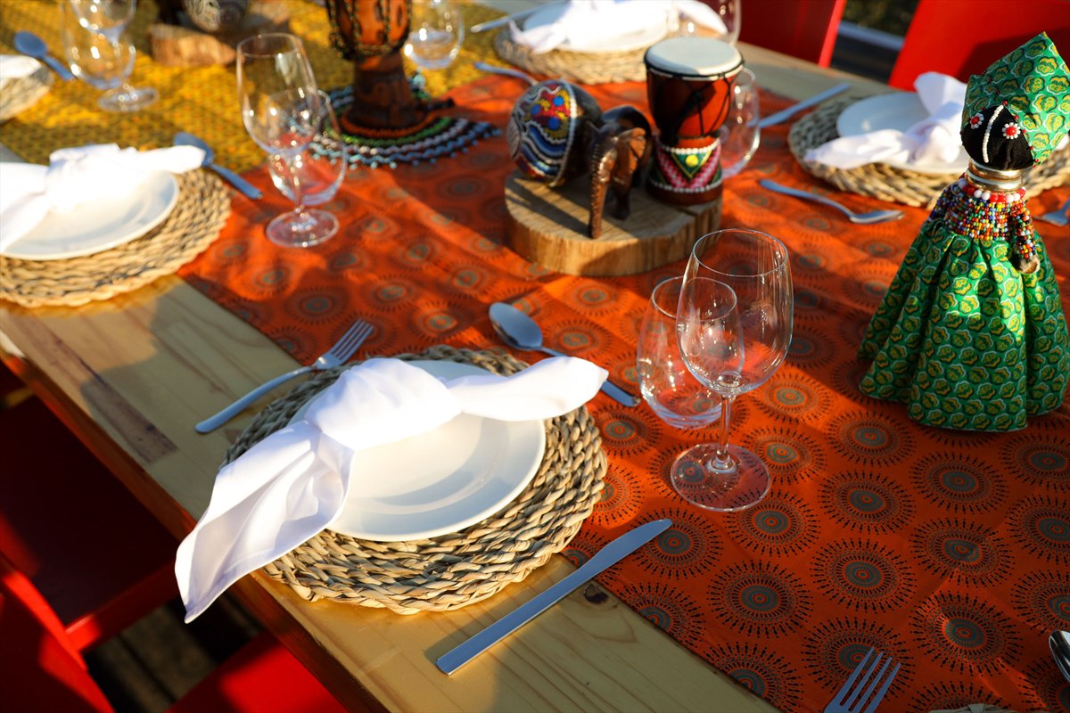 Place settings, wine glasses, small drums and colourful decorations on a patterned table runner