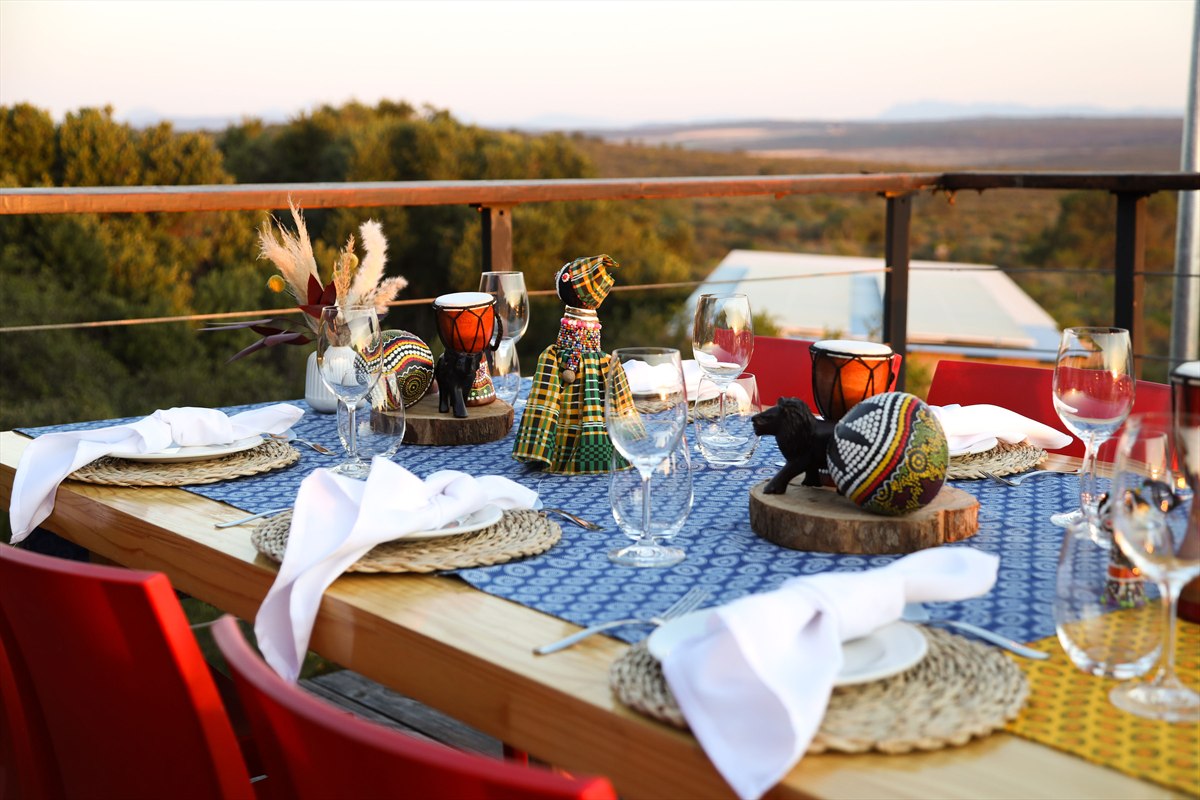 Outdoor dining table with white napkins, a blue patterned runner and colourful centrepieces
