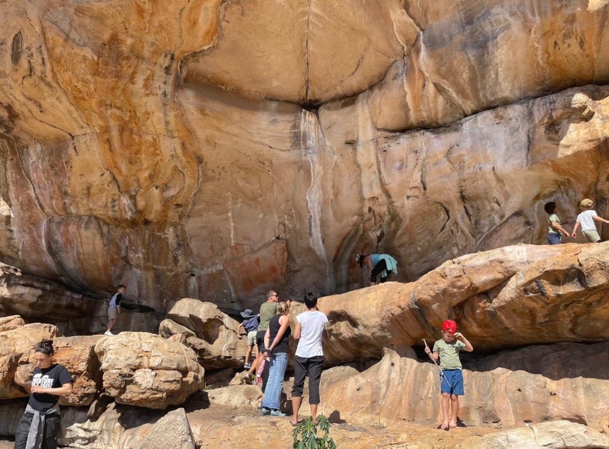 Adults and children exploring a tall sandstone rock face at Donkieskraal
