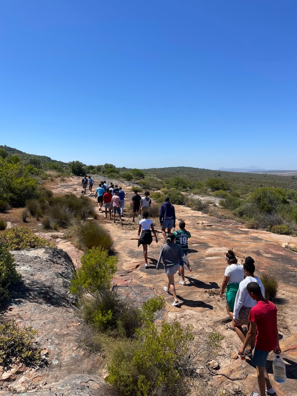 Group of hikers walking across a broad sandstone trail at Donkieskraal