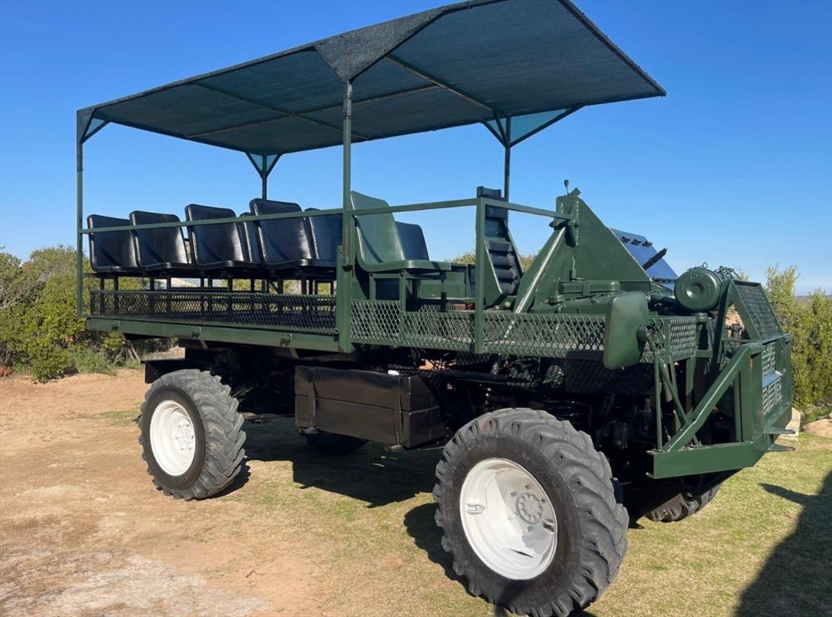 Open green game-drive vehicle parked beneath a clear blue sky at Donkieskraal