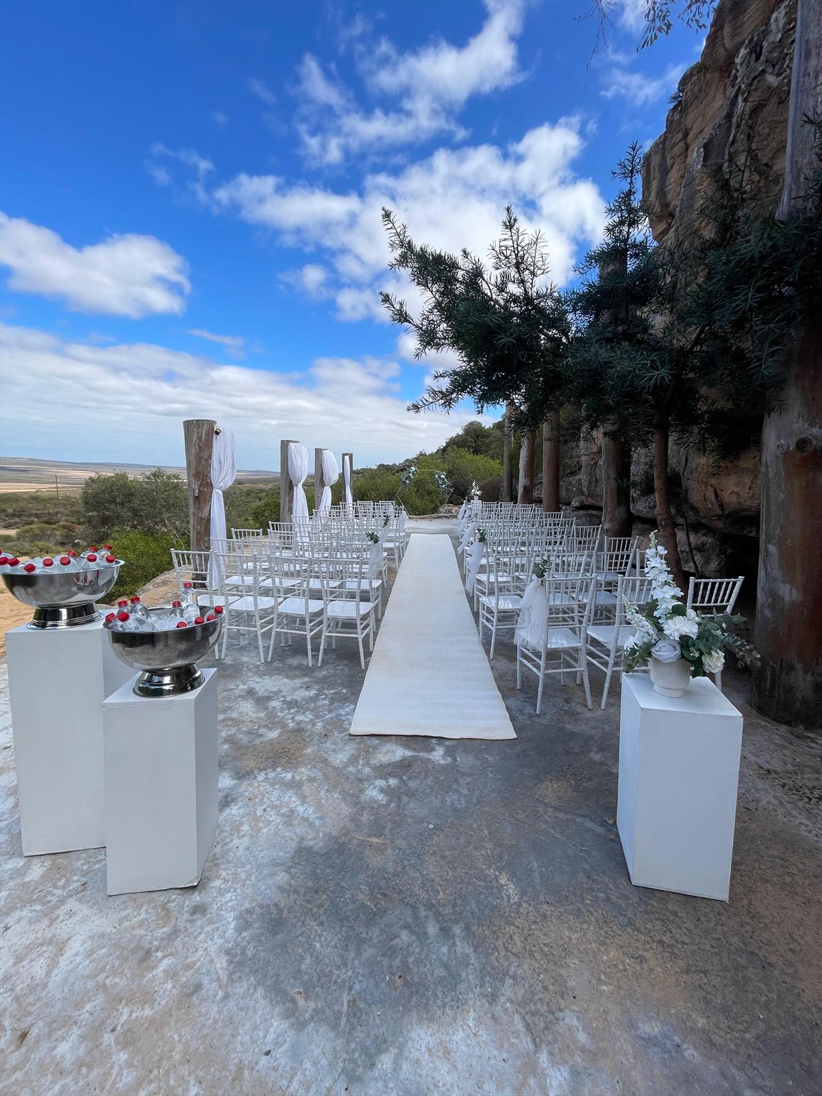 White chairs and a ceremony aisle set beside the rock venue at Donkieskraal