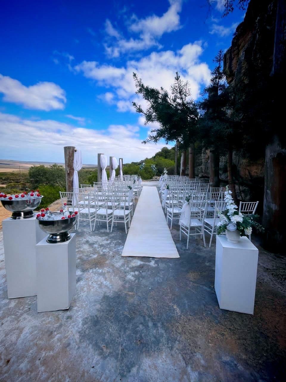 Outdoor wedding ceremony aisle with white chairs beneath a blue sky at Donkieskraal